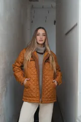 Campera acolchada color ladrillo con cuello marrón de pana, cierre frontal con botones a presión y bolsillos laterales.