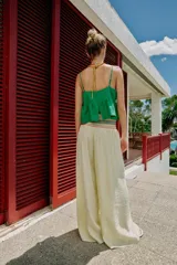 Top corto de lino color verde, con escote en pico, tirantes finos ajustables y detalle de ondas decorativas en color crema. Presenta un diseño con vuelo en la parte inferior y cierre en la espalda.