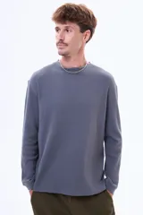 Buzo de manga larga con textura tipo waffle, cuello redondo y corte holgado.