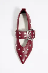 Bailarinas negras de cuero con punta fina, tachas plateadas y correa con hebilla metálica. Zapato plano con suela fina.