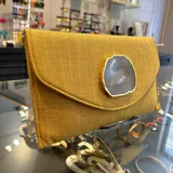 Sobre de fiesta color mostaza, hecho artesanalmente en la India, con aplique de piedra ágata a tono. Incluye asa de cadena dorada para llevar al hombro.