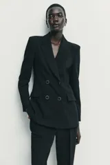 Blazer de corte estructurado con hombreras, cuello solapa y manga larga. Presenta un diseño cruzado con cierre frontal de botones y bolsillos delanteros con solapa.