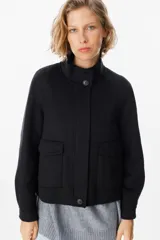 Chaqueta corta de paño color gris, con cuello alto, cierre frontal con cremallera y bolsillos delanteros con solapa.