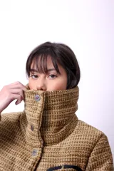 Campera color tostado con textura, cierre frontal con botones a presión, cuello alto y bordado negro "CP" en el frente. Tiene forro interior y relleno liviano de guata.