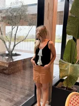 Musculosa tejida negra con escote en V y tirantes finos, con detalle de aplique frontal en forma de flecha de cuero plateado.