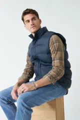 Chaleco color camel de nylon con cierre frontal con broches a presión, cuello alto y bolsillos laterales.