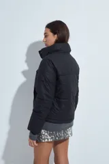 Campera puffer de nylon color marrón oscuro, con cuello alto, cierre frontal y puños elásticos. Diseño acolchado de volumen ligero.