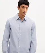 Camisa de vestir para hombre, de manga larga y calce clásico, confeccionada en tricolina de algodón y poliéster, con diseño de cuadros grid en tono celeste claro. Presenta cuello camisero, cierre frontal con botones y puños ajustables con botón único.