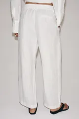 Pantalón de tiro medio confeccionado en 100% lino. Presenta cintura elástica con trabillas, bolsillos laterales, detalle de pinzas en el delantero y cierre frontal con cremallera y botón.