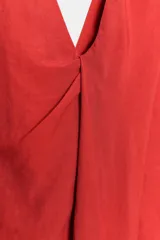 Vestido midi de Zara Woman Collection color rojo, confeccionado con mezcla de lino. Presenta escote en V pronunciado, mangas sisa y un diseño con frunce delantero y detalle drapeado. Cuenta con bajo recto y cierre lateral con cremallera oculta.