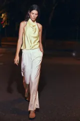 Top de satén color amarillo pastel, con diseño de cuello halter y espalda descubierta. Presenta una caída fluida y elegante, con un corte minimalista que se ajusta suavemente al cuerpo.