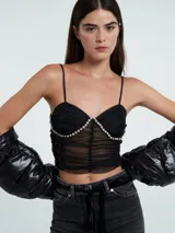Top negro de encaje con escote corazón, breteles finos y detalle de strass en el busto.