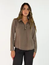 Remera de manga larga con cuello polo y cierre frontal de dos botones. Presenta un diseño de corte recto y acabado desgastado en las costuras.