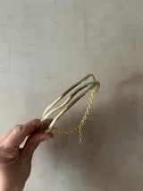 Gargantilla de bronce dorada con tres aros ondulados y cadena de ajuste.