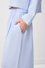 Pijama de algodón a rayas celestes y blancas, compuesto por una camisa de manga larga con botones y un pantalón largo de corte ancho.