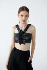 Top corto de cuero sintético negro con breteles fruncidos con elástico y volado central. Espalda unida por tiras elastizadas y fruncidas.