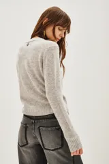 Sweater de punto color negro, con cuello redondo y mangas largas con puños acanalados.