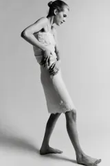 Falda midi de tejido ligero color crema o beige muy claro, con cintura elástica de color beige más oscuro. El bajo está adornado con una aplicación de encaje floral a tono.