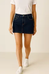 Falda mini de jean en color azul oscuro, con costuras en contraste color ocre, cierre frontal con botón y bolsillos laterales.