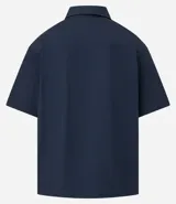 Camisa de manga corta Ripping, confeccionada en tricolina de algodón. Presenta un corte boxy relajado, cuello inglés, cierre frontal con botones y dos bolsillos cargo en el pecho con etiqueta bordada.