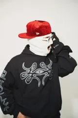 Hoodie negro oversize de algodón con capucha y pasamontañas desmontable con cierre. Presenta estampa en plastisol en el pecho y en ambas mangas.