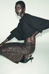 Jersey corto de punto color negro, con cuello barco y mangas largas abullonadas, terminadas en puño.