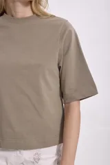 T-shirt de manga corta, color verde oliva o caqui, con cuello redondo y corte holgado.