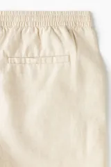 Short de mezcla de algodón y lino color beige, con cintura elástica con cordón de ajuste, botón frontal, bolsillos laterales y corte estándar.
