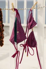 Traje de baño de dos piezas con estampado geométrico en tonos borgoña y gris. El corpiño es triangular con tiras finas y ajustables. La bombacha es de corte vedetina con tiras laterales para atar.