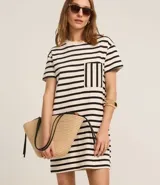 Vestido corto estilo camiseta de algodón, con cuello redondo, mangas cortas y bolsillo en el pecho. Presenta un patrón de rayas horizontales blancas y negras.