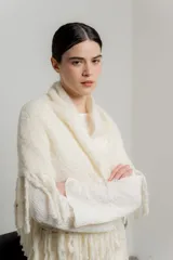 Chal de punto color crudo con textura suave y terminaciones con flecos largos en todo el borde.