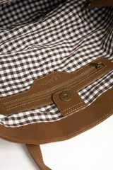 Bolso tipo tote bag de tamaño maxi color suela, confeccionado en material sintético con textura efecto cuero gastado. Cuenta con doble asa de hombro y placa metálica con la inscripción de la marca en la parte frontal.