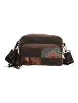 Cartera bandolera de diseño patchwork que combina paneles de tela marrón lisa con secciones de tejido estampado con motivos geométricos y florales. Cuenta con cierre de cremallera en el compartimento principal, bolsillo trasero, correa ajustable y desmontable, y un detalle de borlas decorativas con dijes en uno de los laterales.
