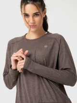 Polera de manga larga en color marrón chocolate con efecto melange. Presenta cuello redondo, mangas raglán, puños elásticos y cintura con ajuste elástico. Incluye un pequeño logo bordado en el pecho.