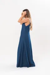Vestido largo de denim fino y liviano, color azul, con breteles finos, escote en V y falda amplia con recortes verticales y bolsillos laterales.