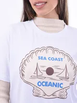 Remera blanca de manga corta con estampado frontal de una tortuga marina rodeada de corales y la frase "OCEAN LIFE".