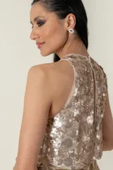 Vestido corto dorado de tul bordado, con cuello halter y falda ajustada.