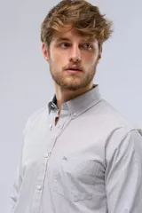 Camisa celeste a rayas verticales, de manga larga con opción de enrollar, corte slim fit, con bolsillo en el pecho y confeccionada en algodón.