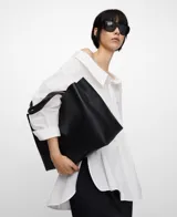 Bolso shopper horizontal negro de piel sintética, con dos compartimentos, cierre magnético y bolsillo interior con cremallera. Cuenta con asa de mano y correa larga regulable y extraíble, además del logo grabado en el frente.