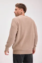 Sweater de punto grueso en color marrón, con cuello redondo y diseño de textura acanalada. Presenta un corte holgado y mangas largas.