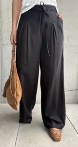 Pantalón negro de lino con pinzas en la cintura, cordón ajustable y corte wide leg.