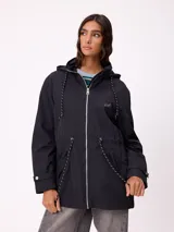 Rompevientos negro con capucha ajustable mediante cordones, cierre frontal de cremallera y ajuste en la cintura con cordón. Presenta logo de la marca bordado en el pecho y puños con detalle de botón.