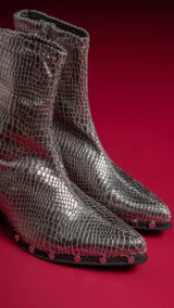 Botas cortas plateadas con textura de piel de serpiente, taco cuadrado y cierre lateral.
