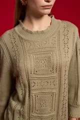 Sweater acrílico en tono natural, de corte holgado, con cuello a la base decorado con sutiles volados, mangas 3/4 y diseño tejido con motivos geométricos calados en el frente.