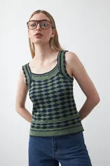 Top sin mangas tejido con diseño geométrico en relieve en colores verde y azul marino. Presenta escote cuadrado y breteles tejidos con terminaciones trabajadas.
