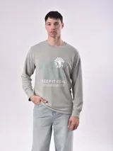 Buzo verde claro con estampado frontal con la frase "Keep it real" y un diseño floral.