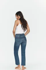 Jeans de tiro alto con diseño cropped flare, confeccionados en denim azul con acabado desgastado. Presentan cinco bolsillos, cierre frontal con cremallera y botón metálico, y bajo con terminación sin costuras.