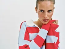 Sweater de punto con diseño de rayas horizontales en rojo y celeste, cuello polo blanco con escote en V y manga larga.