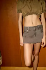 Falda corta de denim color marrón grisáceo, tiro bajo, con cierre frontal de doble botón y bajo deshilachado.