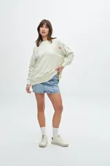 Buzo celeste de corte holgado con cuello redondo y mangas largas. Estampado en la espalda con la frase "Chasing sunbeams through fields of flowers".